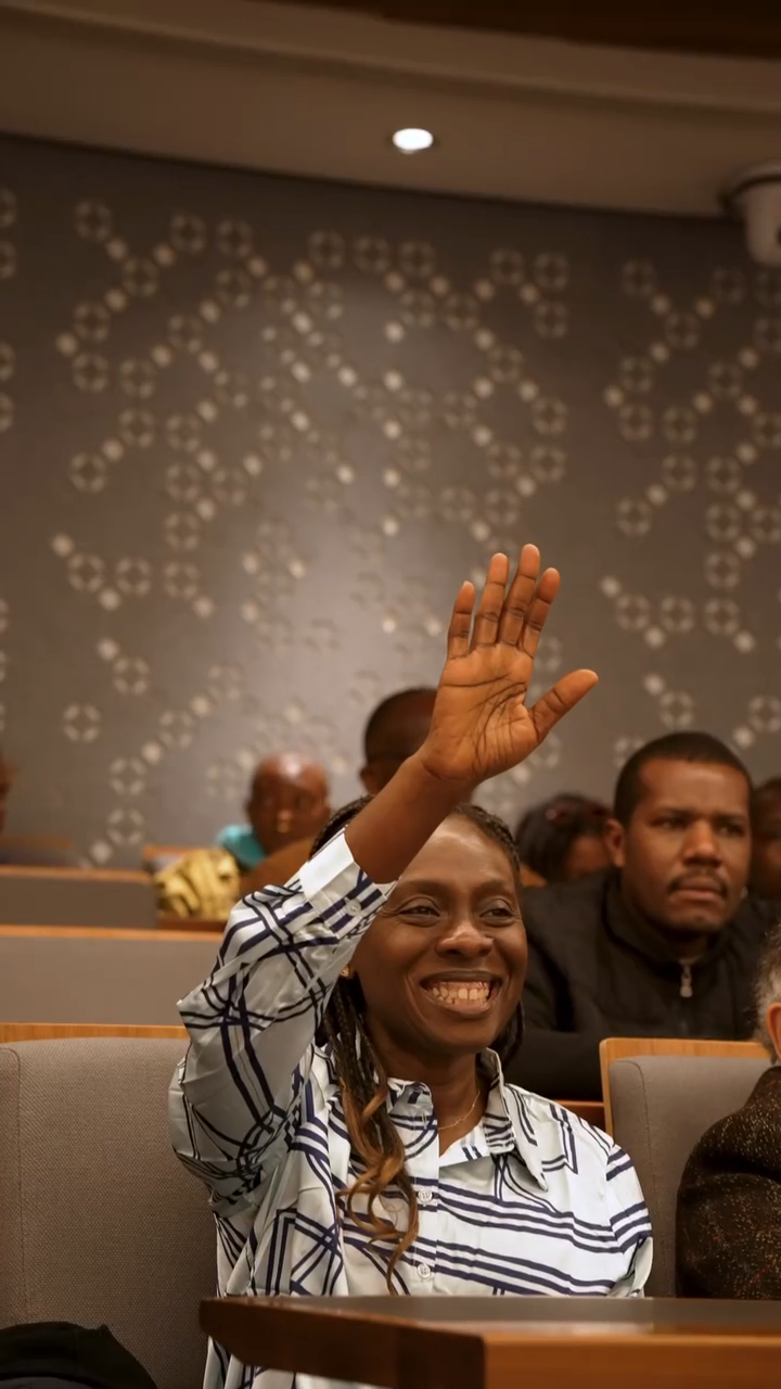A student smiling and raising both hands in the air, clearly engaged and joyful during the film screening.