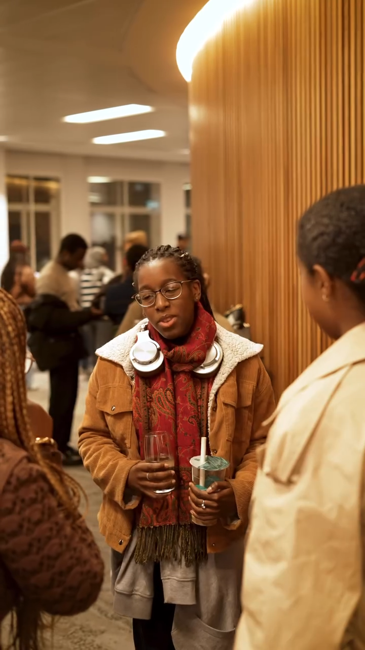 Bolanle Austen‑Peters chatting and smiling with two students in the lobby after the screening.