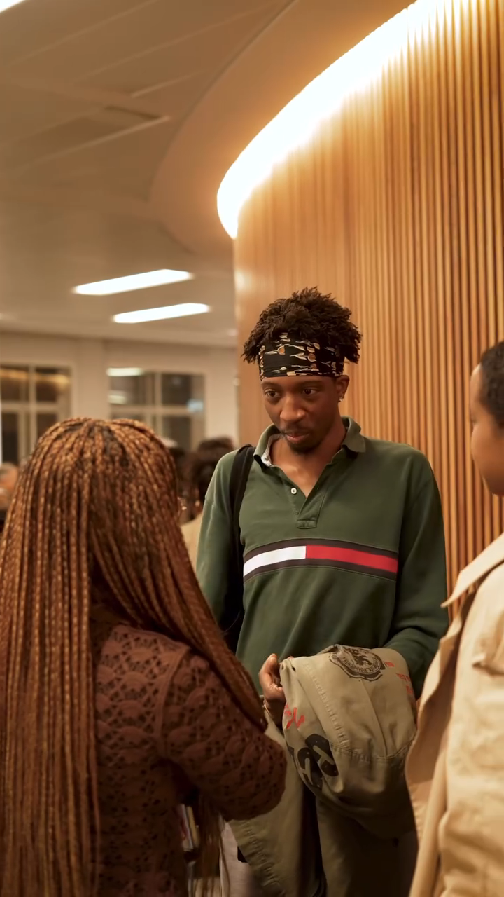 Bolanle Austen‑Peters chatting and smiling with two students in the lobby after the screening.